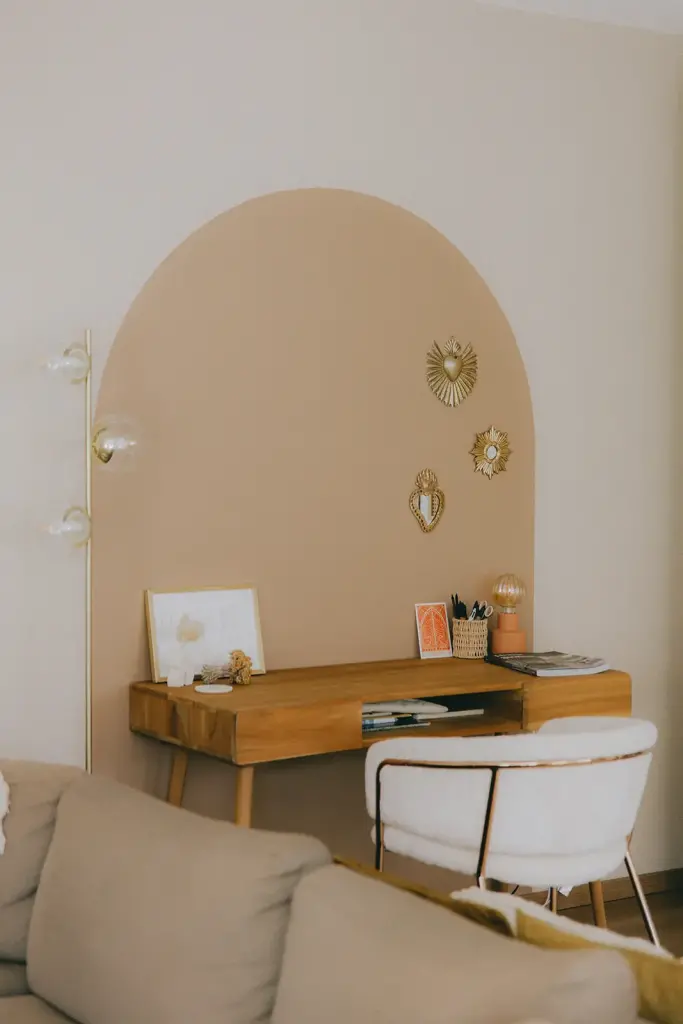 Bureau en bois sous une arche rose, fauteuil en cannage
