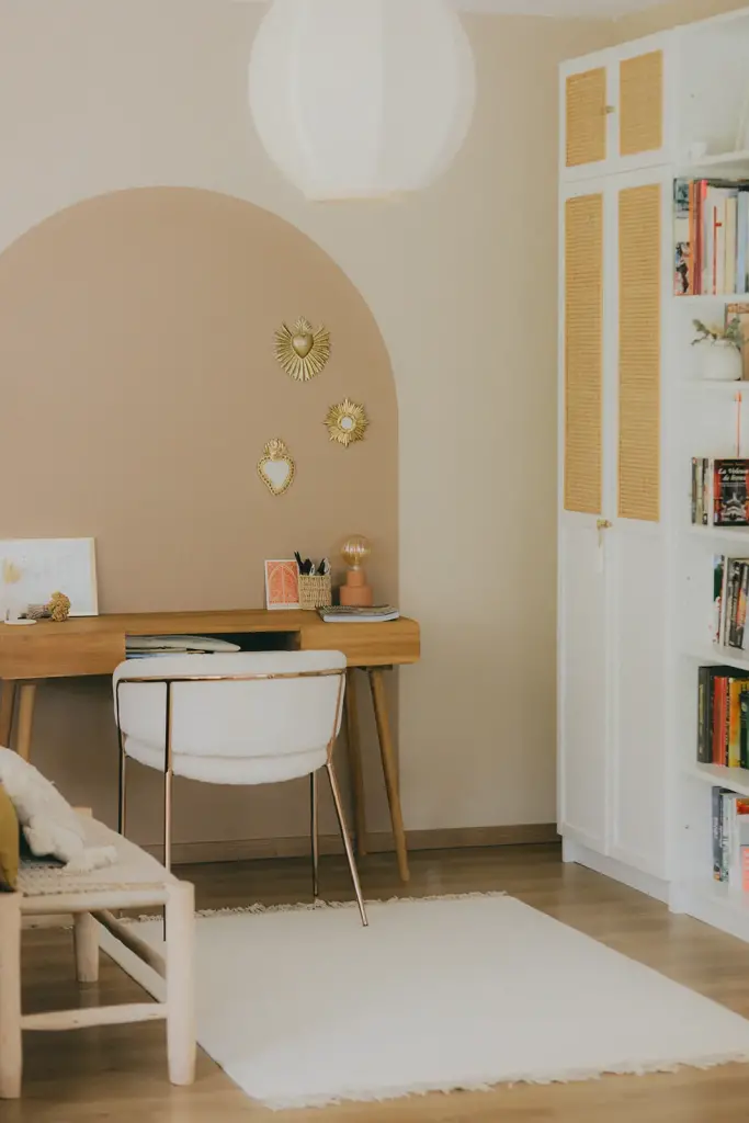 Coin bureau sous une arche rose, bibliothèque blanche et tapis clair