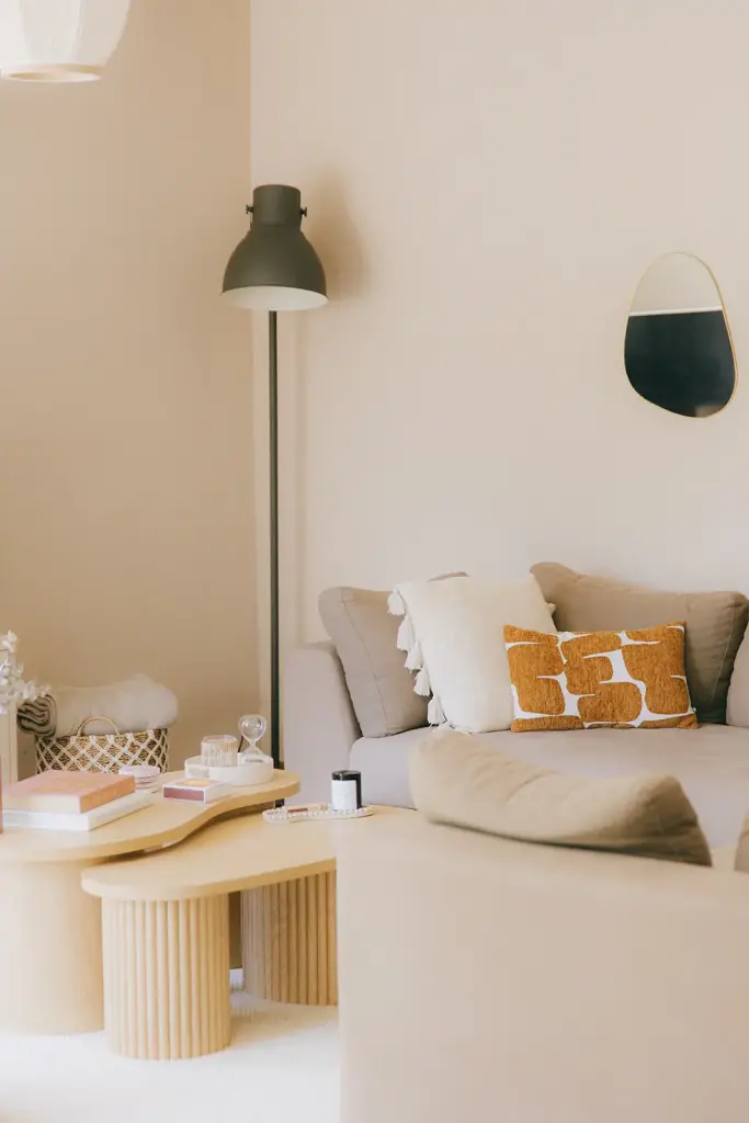 Lampe noire près d’un canapé aux coussins ocre, appliques au mur
