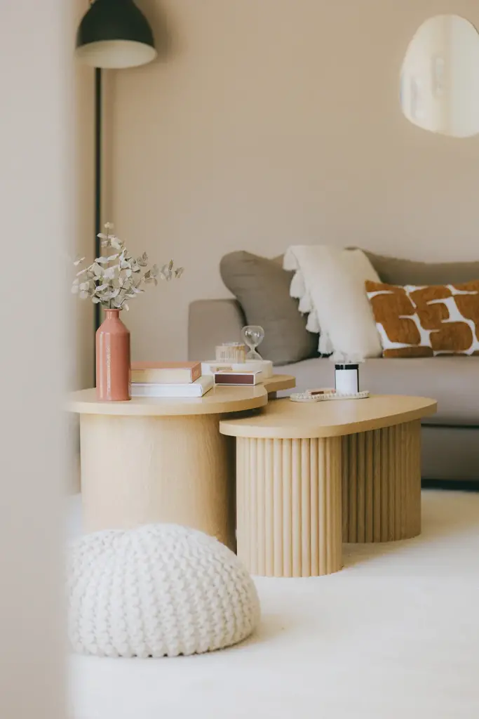 Tables basses cannelées en bois clair, pouf en tricot et coussins ocre